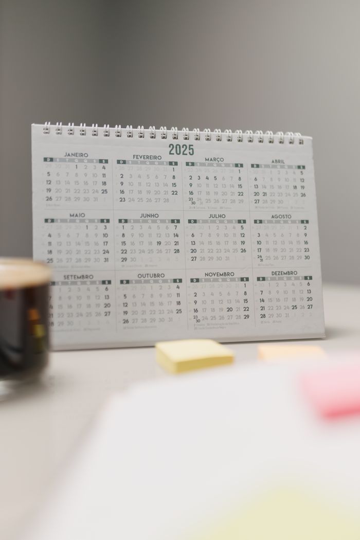 A clean and organized desk setup with a 2025 calendar and sticky notes, perfect for planning.